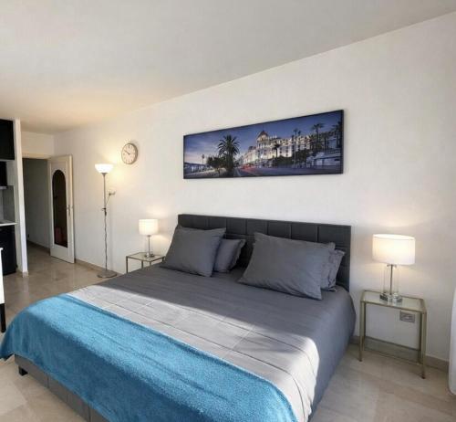 a bedroom with a large bed with blue sheets and two lamps at Studio Premium au Calme avec Terrasse Vue Mer et Parking in Nice