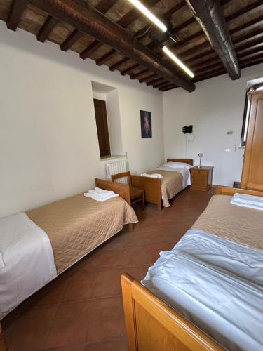 a room with three beds and a table and chairs at Casa per Ferie Ulivo d'Assisi in Assisi