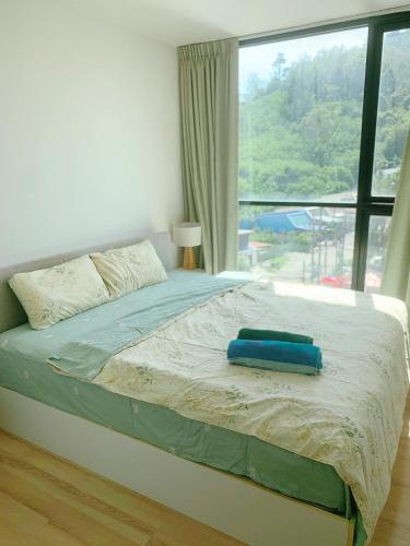 a bedroom with a bed with a large window at The Base Height Phuket in Phuket