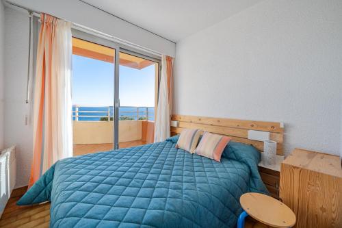 a bedroom with a blue bed and a large window at Résidence "Le Golfe Bleu" in Roquebrune-Cap-Martin