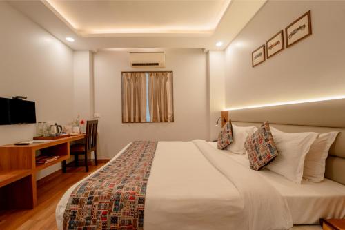 a hotel room with a bed and a desk and a television at HHW Hotel- Agra in Agra