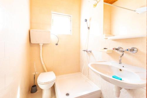 a white bathroom with a toilet and a sink at Apartmani Danijela in Stara Novalja