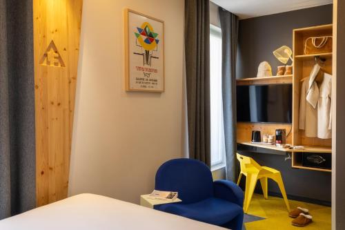 a hotel room with a blue chair and a desk at Urban Bivouac Hotel in Paris