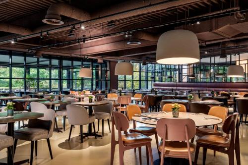 a restaurant with tables and chairs and windows at Residence Inn by Marriott Amsterdam Schiphol Airport in Badhoevedorp