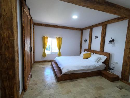 a bedroom with a bed and a window with yellow curtains at Wildglowlodge in Petroşani