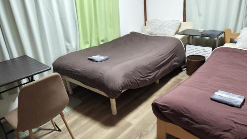 a room with two beds and a table and chairs at 102個室元芸者の隠れ宿湯河原 in Yugawara