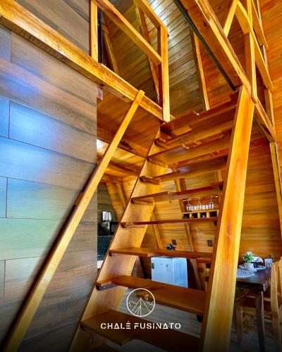 an attic of a wooden house with a wooden staircase at Chalé Fusinato in Witmarsum