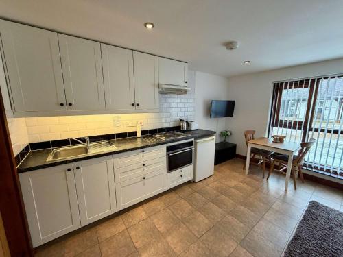 a kitchen with white cabinets and a table with a dining room at Millbrook House Apartments 8 in Milton