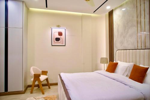 a white bedroom with a bed and a chair at Executive 2BHK in Zeta Mall in Islamabad