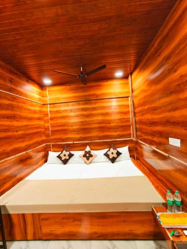 a bed in a wooden room with a ceiling at KHATWADi in Ujjain