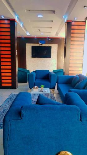a living room with blue couches and a flat screen tv at فندق جولدن نيو روز بلازا جازان in Jazan