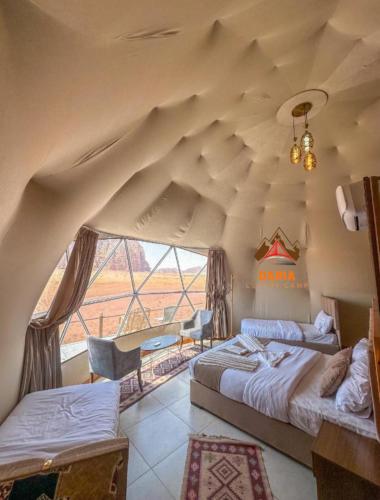 a bedroom with two beds and a large window at Daria Luxury Camp in Wadi Rum