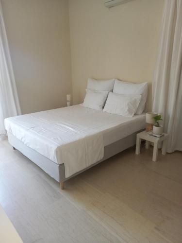 a white bedroom with a bed with white sheets and pillows at Narika Aether in Kamena Vourla