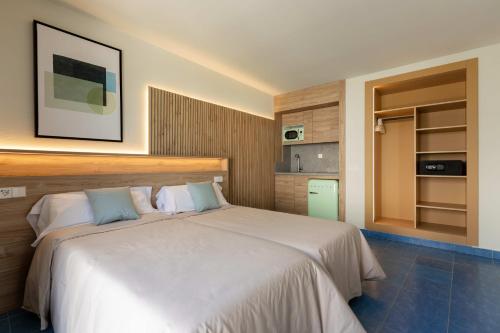 a bedroom with a large white bed and a kitchen at The Blue Apartments - Adults Only in San Antonio