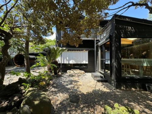 a black house with a tree and a building at AKAMA Kamakura in Kamakura