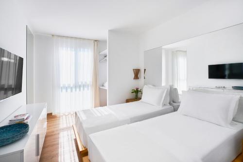 a white room with two beds and a tv at Flamm Residences in Bodrum City