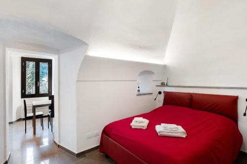 a red bed in a white room with a desk at Casa vacanza A Cola - con Jacuzzi in Rocchetta Nervina