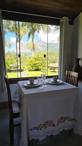 a table with two wine glasses and a window at Chalé Vista Pedra Azul in Domingos Martins