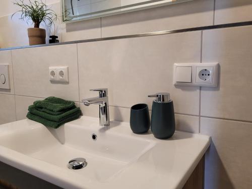 a bathroom sink with two cups sitting on it at Ferienwohnung Obstgarten in Halblech