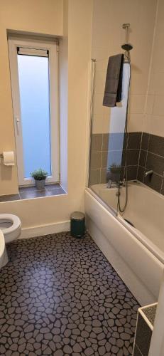 a bathroom with a tub and a toilet and a window at Beautiful City Centre House with Parking! Sleeps 6 in Sheffield