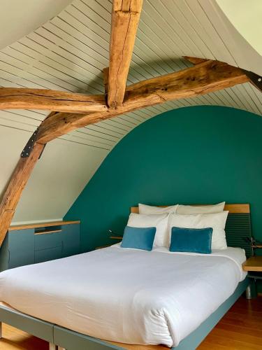 a bedroom with a large white bed with a green wall at Suites du Cabinet Vert in Orléans