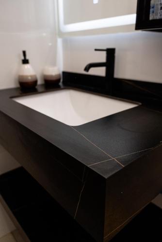 a bathroom counter with a sink and a black counter top at T3 Elegance x Nawassi Moderne, climatisé, sécure in Pamandzi