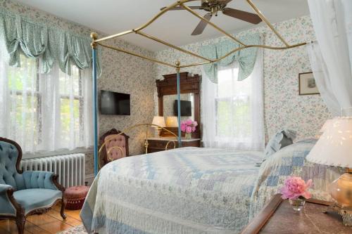 a bedroom with a canopy bed and a blue chair at The Queen Victoria in Cape May