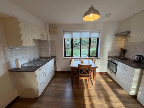 a kitchen with white cabinets and a table and a window at Millbrook House Apartments 3 in Milton