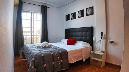 a bedroom with a bed with a red pillow on it at Apartalux Vista Mar in La Manga del Mar Menor