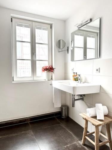 a white bathroom with a sink and two windows at Adler Hotel und Restaurant Schiltach in Schiltach
