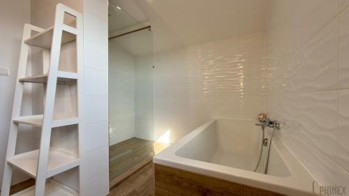 a white bath tub in a bathroom with shelves at Priestranný apartmán s veľkorysým výhľadom in Rača