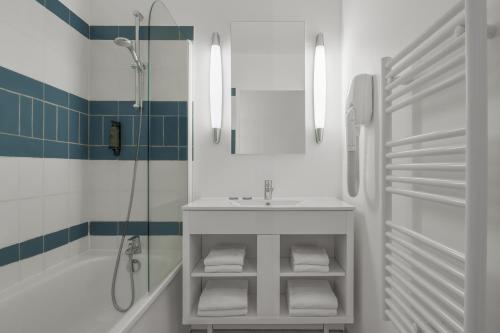 une salle de bain blanche avec un lavabo et une douche dans l'établissement Citadines Bastille Gare de Lyon Paris, à Paris