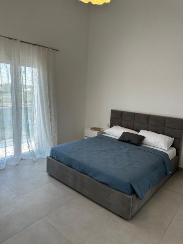 a bedroom with a large bed with a blue blanket at Modern Getaway Meets Nature in Ishull-Shëngjini