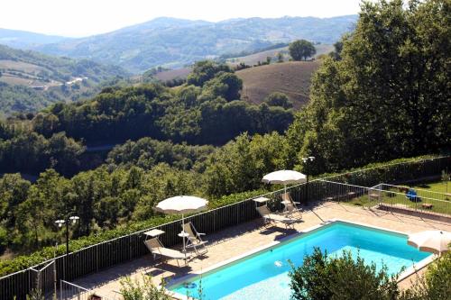 a swimming pool with two chairs and umbrellas at Agriturismo La Coccinella in Valfabbrica