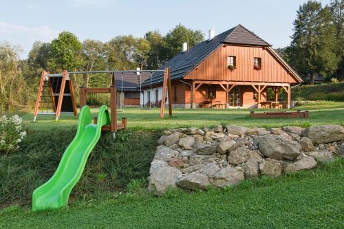 a playground with a green slide in front of a house at Chalupa Pod Šerovnou in Prachatice