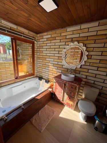 a bathroom with a tub and a toilet and a sink at Chalé Miragem dos Canyons in Praia Grande
