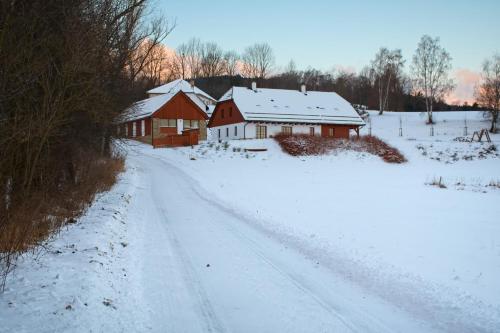 a snow covered road next to two barns at Chalupa Pod Šerovnou in Prachatice