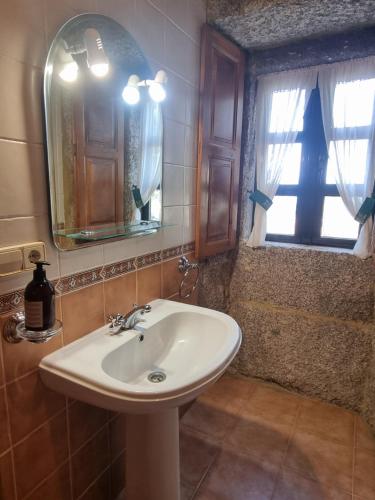a bathroom with a sink and a mirror and a window at A Regueira Habitaciones in Alján
