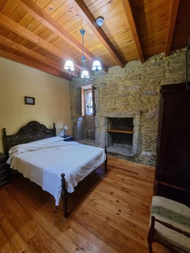 a bedroom with a bed and a stone fireplace at A Regueira Habitaciones in Alján