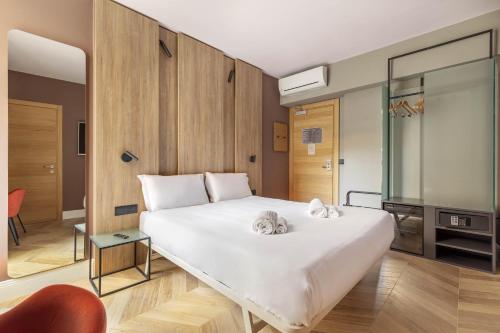 a bedroom with a large white bed and a chair at B&B Hotel Genova City Center in Genoa
