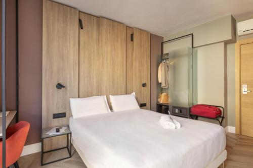 a bedroom with a large white bed and a red chair at B&B Hotel Genova City Center in Genoa