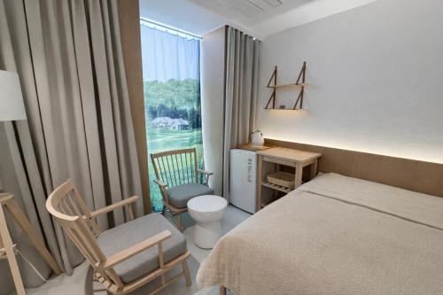 a bedroom with a bed and a chair and a window at 제주 디스피어 호텔 D-Sphere in Jeju