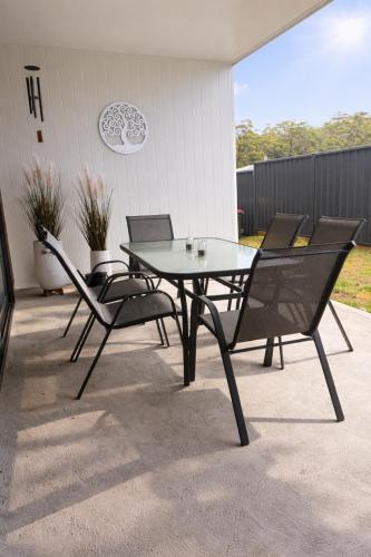 ein Glastisch und Stühle auf einer Terrasse in der Unterkunft Azure Abode in Broulee