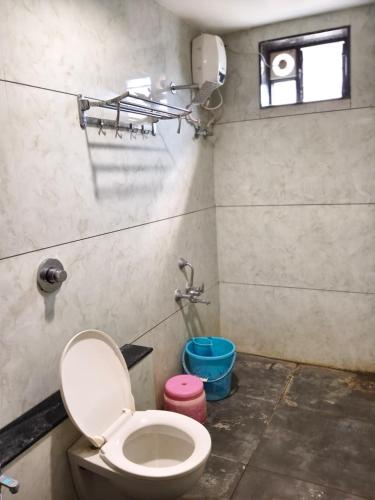 a bathroom with a toilet and a window at Hotel Baroda Rooms in Vadodara