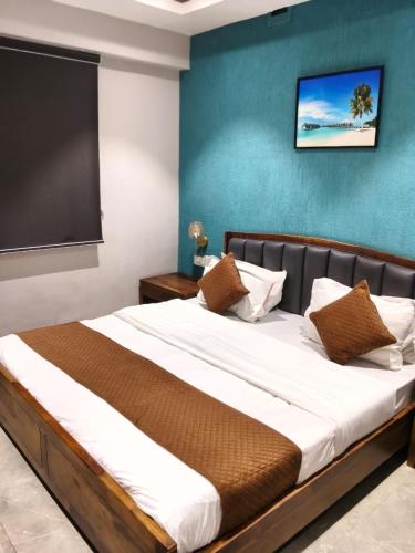 a bedroom with a large bed with a blue wall at Hotel Baroda Rooms in Vadodara