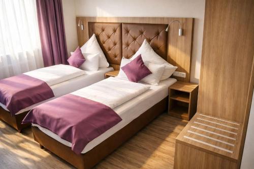 a hotel room with two beds with purple and white pillows at Ata Hotel - Self Check-in in Hamburg