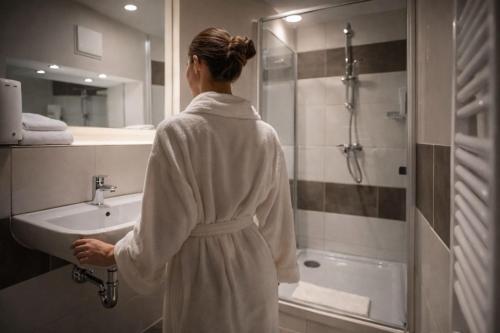 a woman standing in front of a sink in a bathroom at Ata Hotel - Self Check-in in Hamburg