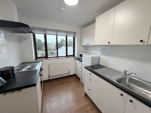 a kitchen with white cabinets and a sink and a stove at Millbrook House Apartments 2 in Milton