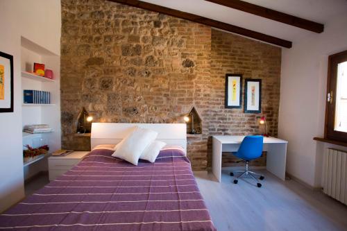 サン・ジミニャーノにあるSan Gimignano Apartmentのレンガの壁のベッドルーム、ベッド1台、デスクが備わります。
