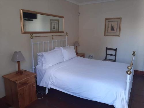a bedroom with a white bed and a mirror at De Kothuize 4 in Graaff-Reinet